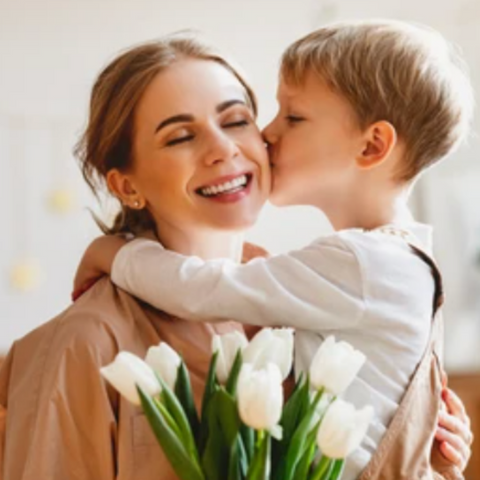 Son loving on his mother. Both the mother and son are happy and kissing each other. 